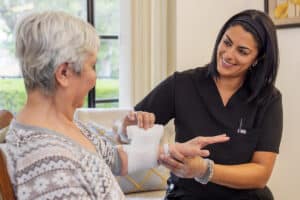 nurse wrapping an arm wound on an elderly resident