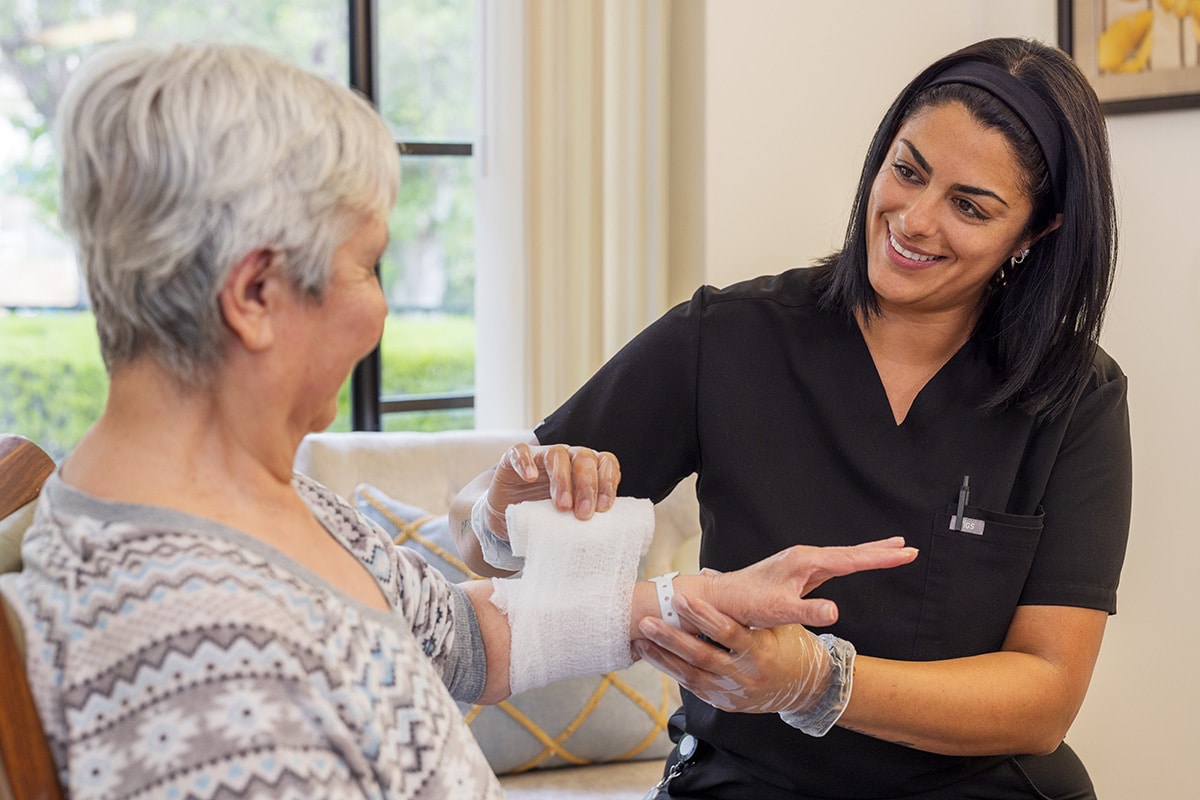 nurse wrapping an arm wound on an elderly resident